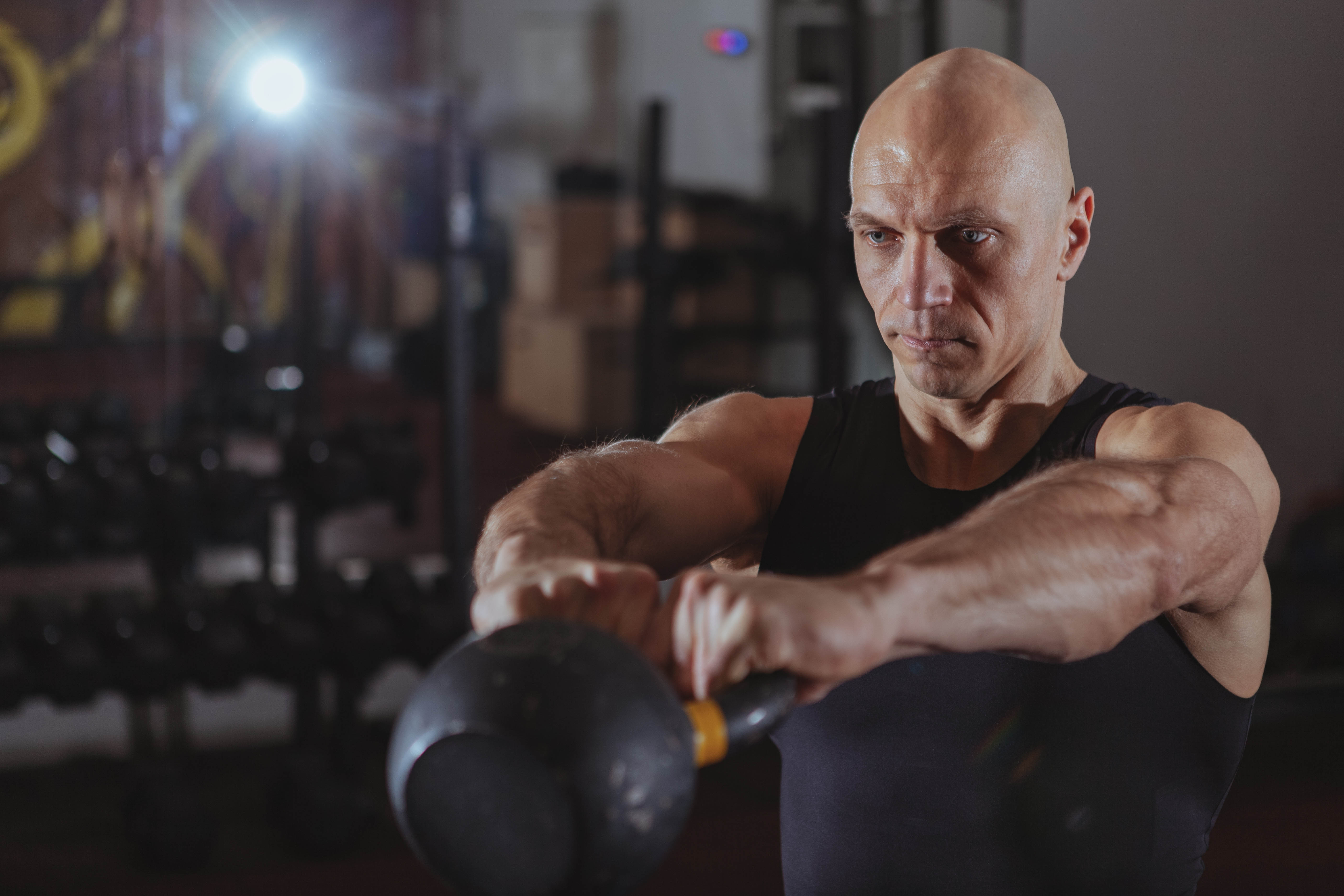 Older man swinging a kettlebell directly in front of his body